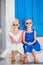 Little happy girls in dresses at street of typical greek traditional village on Mykonos Island, in Greece