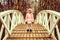 Little happy six year old kid girl in autumn clothes stands on the humpback wooden bridge in the fall park.
