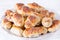 Little homemade croissants with a stuffing on a plate on a white wooden background