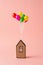 Little house with colorful balloons over pink background. Creative real estate business minimal concept