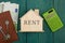little house with text "Rent", keys, calculator, passport, money on blue wooden desk