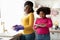 Little Housekeeper. Cute Little Black Girl Helping Mom In Kitchen, Washing Dishes