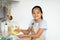 Little housekeeper. Happy asian girl helping mother in kitchen, washing and wiping dishes, standing in kitchen