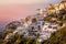 Little houses in the cliff at the city of Oia in Santorini, Greece. .Pink skies fills the sky