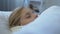 Little ill female kid in scarf lying in bed, suffering grippe, seasonal disease