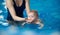 Little infant swimmer. Cropped view of mother training her newborn baby floating in swimming pool. Baby diving in water