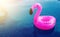 A little inflatable flamingo swims in a pool in the sunlight. Coasters for the pool. The concept of summer pastime. Beach summer