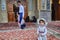 Little Iranian girl wearing beach cap stands in mosque courtyard