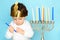 Little jewish boy puts candles on traditional menorah.