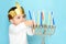 Little jewish boy puts candles on traditional menorah.