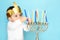 Little jewish boy puts candles on traditional menorah.