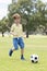 Little kid 7 or 8 years old enjoying happy playing football soccer at grass city park field running and kicking the ball excited i