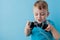 Little kid boy 2-3 years old wearing blue clothes hold in hand joystick for gameson blue background children studio portrait.