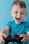 Little kid boy 2-3 years old wearing blue clothes hold in hand joystick for gameson blue background children studio portrait.