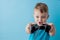 Little kid boy 2-3 years old wearing blue clothes hold in hand joystick for gameson blue background children studio portrait.