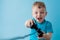 Little kid boy 2-3 years old wearing blue clothes hold in hand joystick for gameson blue background children studio portrait.