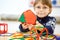 Little kid boy building geometric figures with plastic blocks