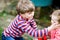 Little kid boy comforts his adorable crying baby sister. Sad toddler girl and lovely brother outdoors.