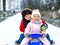 Little kid boy and cute toddler girl sitting together on sledge. Siblings, brother and baby sister enjoying sleigh ride