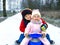 Little kid boy and cute toddler girl sitting together on sledge. Siblings, brother and baby sister enjoying sleigh ride