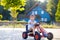 Little kid boy driving pedal race car in summer