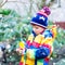 Little kid boy feeding birds in winter. Cute happy preschool child hanging colorful selfmade bird house on tree on