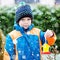 Little kid boy hanging bird house on tree for feeding in winter