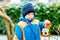 Little kid boy hanging bird house on tree for feeding in winter