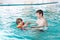 Little kid boy and his father swimming in an indoor pool