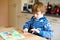 Little kid boy making paper origami tulip flowers for a postcard for mother`s day or birthday. Cute child of elementary