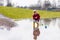 Little kid boy playing with paper ship by puddle