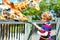 Little kid boy watching and feeding giraffe in zoo. Happy child having fun with animals safari park on warm summer day