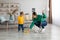 Little kid boy watching her mother mopping the floor after him. Woman wiping the floor with rag next to her baby