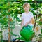 Little kid boy watering plants in greenhouse