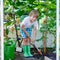 Little kid boy working with garden hoe in greenhouse