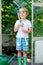 Little kid boy working with garden hoe in greenhouse