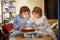 Little kid boys twins celebrating birthday and blowing candles on cake