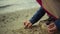 Little kid drawing sand at ocean beach. Child hands playing at sea shore outside