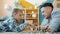 Little kid enjoying chess game with caring father spending leisure time at home