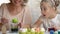 Little kid excitedly watching mom dying egg in green food coloring, Easter decor