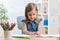 Little kid girl draws sitting at table in room in nursery