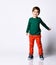 Little kid in green jumper, orange pants and blue sneakers. He is smiling while posing isolated against white background