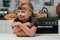 little kid in halloween costume standing at tabletop with pumpkin in kitchen