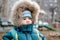 Little kid in the hood with fur and a scarf on the Playground in autumn