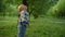 Little kid looking up on flying ball. Funny toddler walking in green forest.