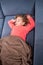 Little kid lying on sofa sleeping with arms up