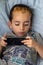 Little kid playing game on smartphone chilling on bed