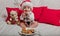 A little kid in a red cap eats a cookies and milk. Christmas photography of a baby in a red cap. New Year holidays and Christmas