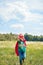 little kid in red superhero cape and mask with outstretched arm running in meadow