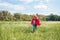 little kid in red superhero cape and mask running in meadow